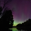 sky with stars colored by the norther lights above river