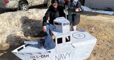Camryn Reynolds stands next to their USS_Cam battleship sled.