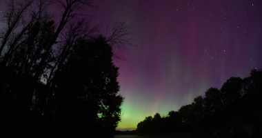 sky with stars colored by the norther lights above river