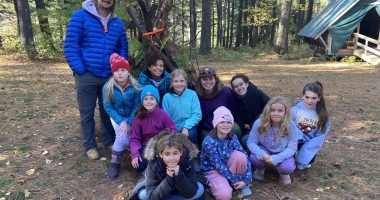 Girl Scouts in front of their lean-to shelter.