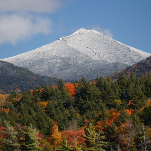 Whiteface Mountain whitecapped with fall trees in the foreground.