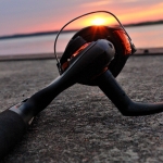 A fishing reel on a sandy beach with a sunset in the background.